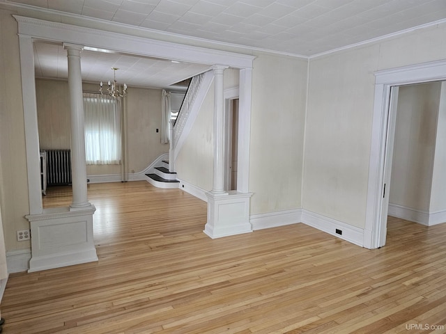 unfurnished living room with radiator, a chandelier, light hardwood / wood-style floors, and ornamental molding