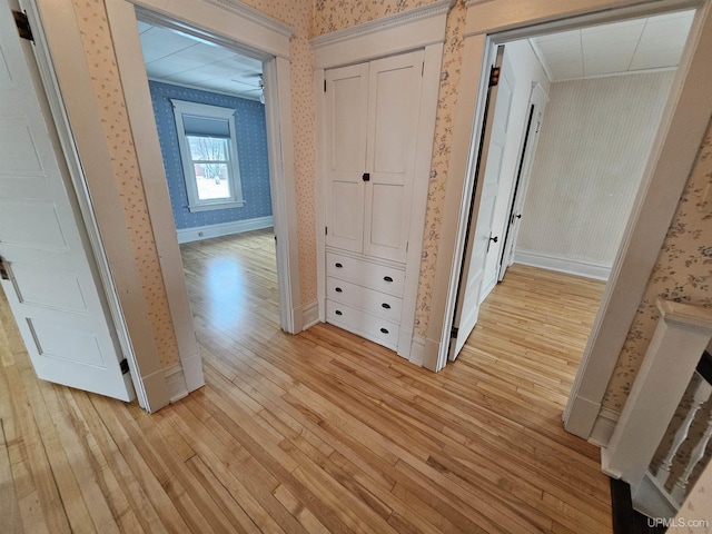 corridor with light hardwood / wood-style flooring and ornamental molding