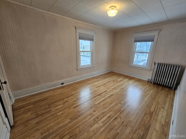 spare room with radiator heating unit and light hardwood / wood-style floors