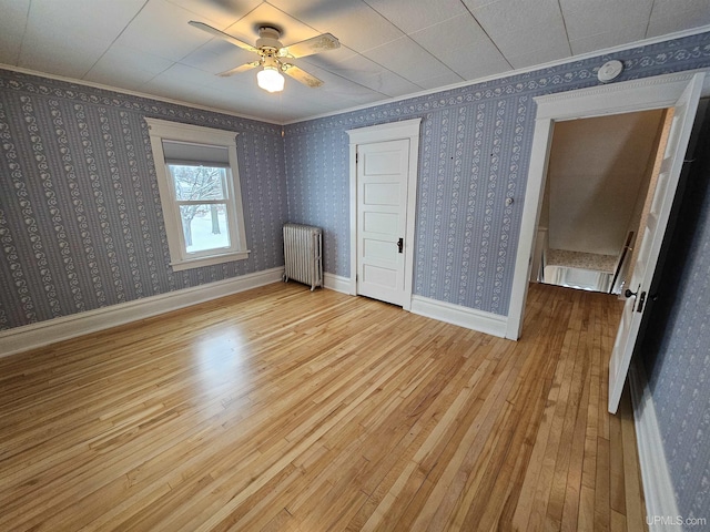 unfurnished bedroom featuring radiator heating unit, light hardwood / wood-style flooring, and ceiling fan