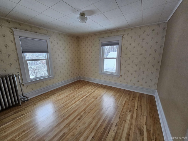 unfurnished room with light wood-type flooring, radiator heating unit, and ornamental molding