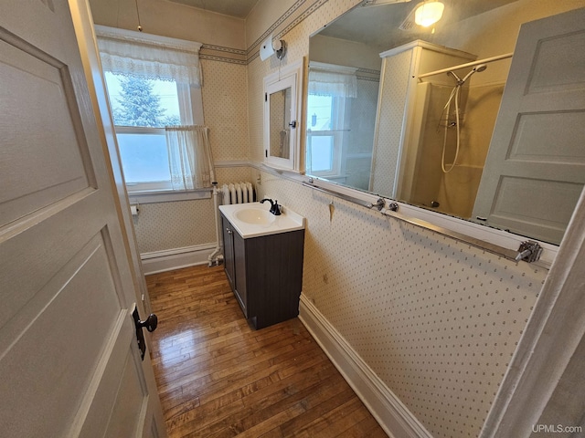 bathroom with hardwood / wood-style flooring, vanity, radiator heating unit, and walk in shower