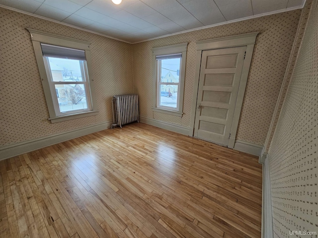 empty room with radiator, light hardwood / wood-style floors, and ornamental molding