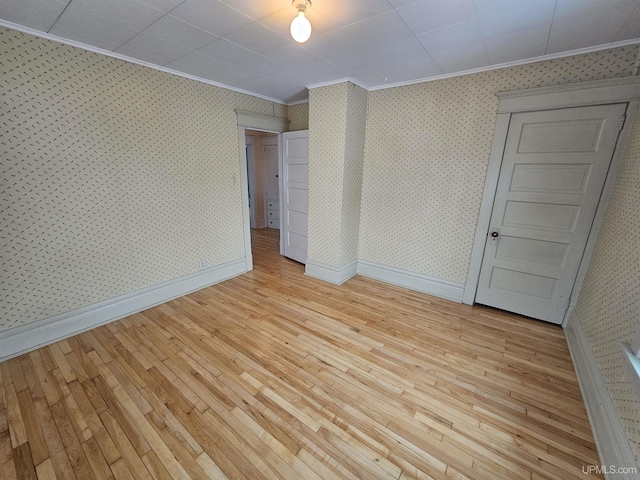 empty room with light hardwood / wood-style floors and ornamental molding