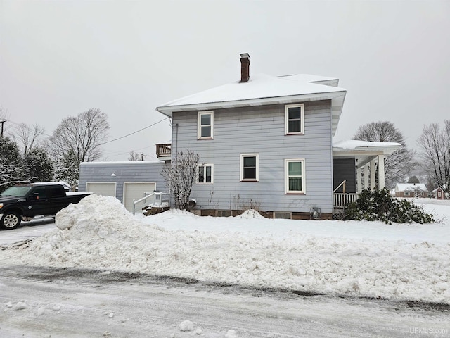 snow covered house with a garage and an outdoor structure