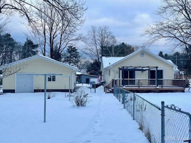 snow covered rear of property featuring a garage and an outdoor structure