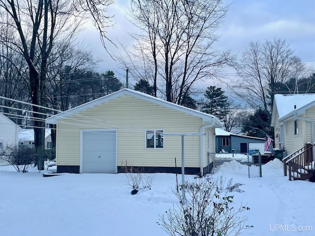 snow covered property featuring a garage and an outdoor structure