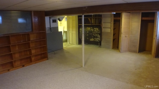 basement with a paneled ceiling and carpet flooring