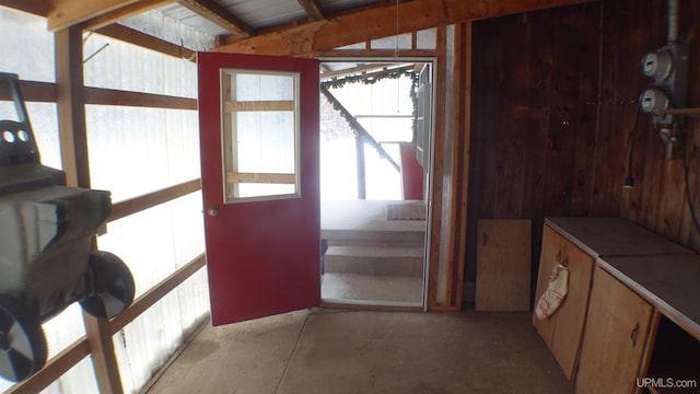 doorway to outside with wood walls