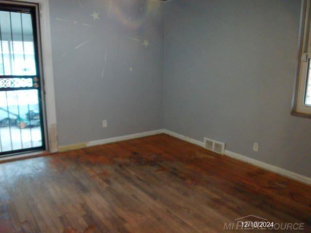 spare room with dark hardwood / wood-style flooring and plenty of natural light