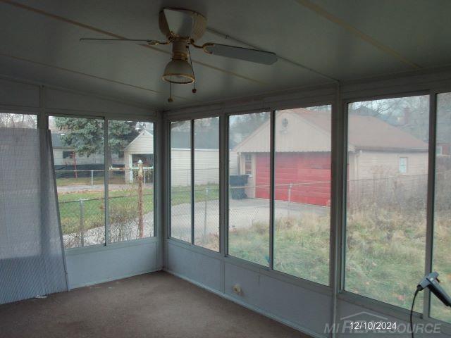 unfurnished sunroom featuring ceiling fan and a wealth of natural light