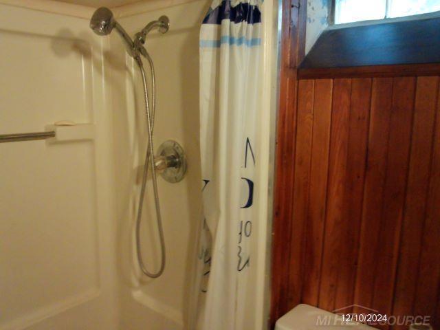 bathroom featuring a shower with shower curtain and wooden walls