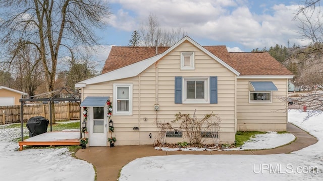 snow covered back of property with a wooden deck