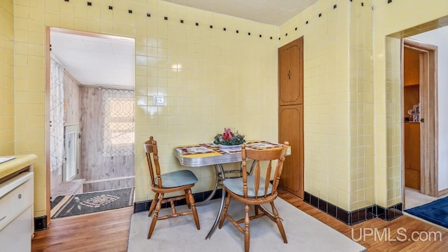 dining room featuring wood-type flooring and tile walls