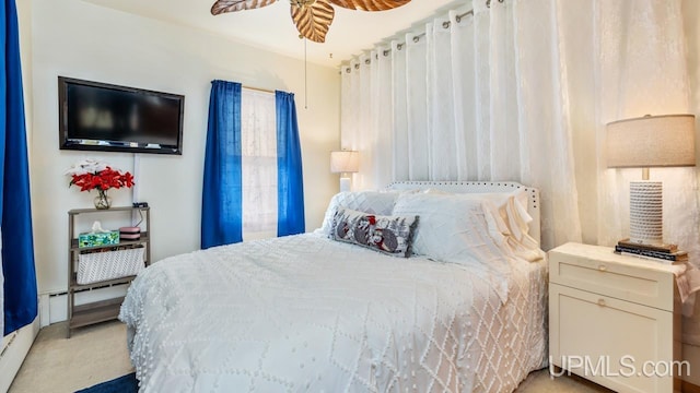 carpeted bedroom featuring ceiling fan and a baseboard heating unit