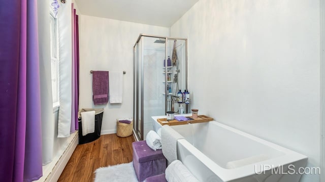 bathroom with hardwood / wood-style flooring, separate shower and tub, and a baseboard radiator