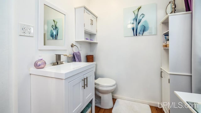 bathroom with hardwood / wood-style floors, vanity, and toilet