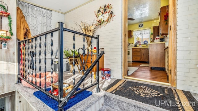 stairway featuring brick wall and hardwood / wood-style flooring