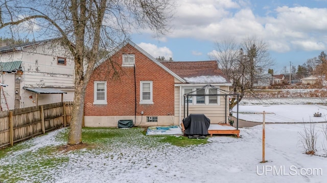 snow covered back of property with a deck