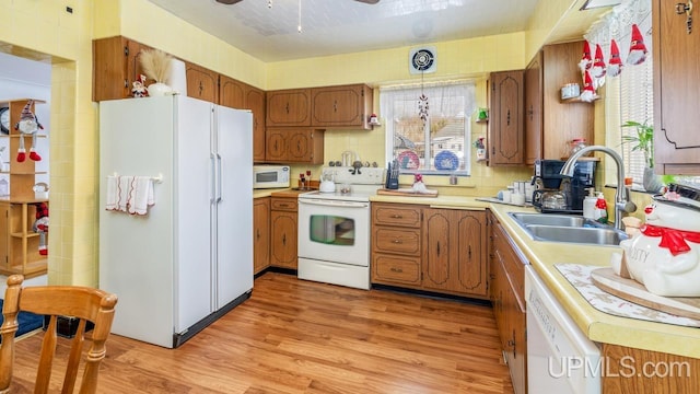 kitchen with white appliances, ceiling fan, sink, decorative light fixtures, and light hardwood / wood-style flooring