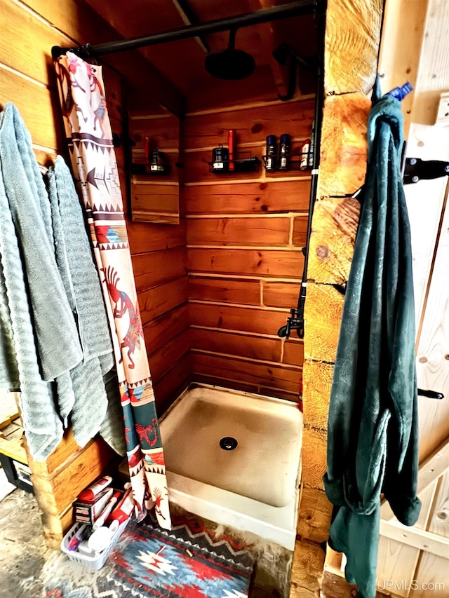 bathroom featuring a shower with shower curtain and wood walls