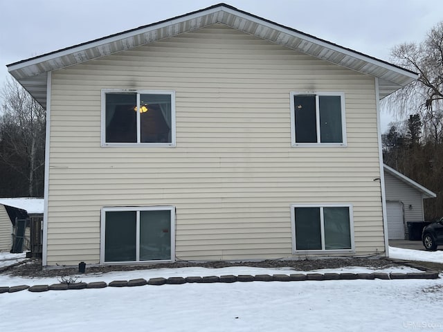 snow covered back of property with a garage