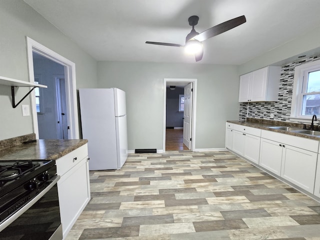 kitchen with white cabinets, white refrigerator, light wood-type flooring, and sink