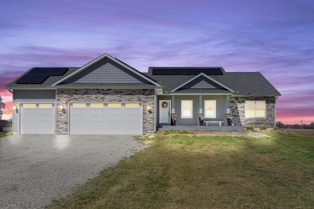 craftsman house with a lawn, covered porch, a garage, and solar panels