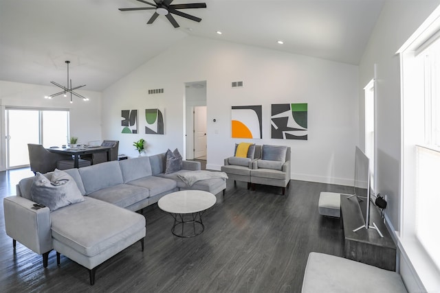 living room with ceiling fan with notable chandelier, dark wood-type flooring, and high vaulted ceiling