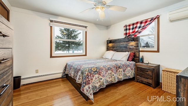 bedroom with a wall mounted air conditioner, light wood-type flooring, baseboard heating, and ceiling fan