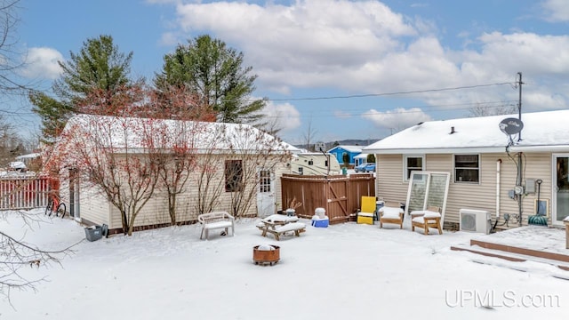 snow covered rear of property featuring a fire pit