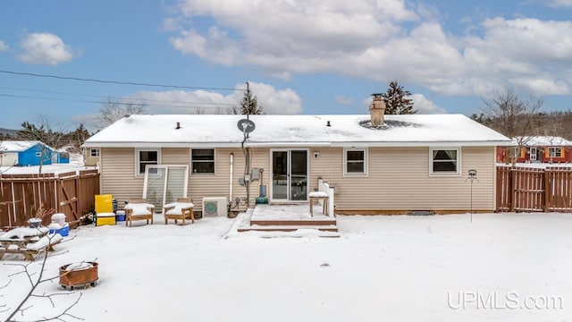 snow covered house featuring ac unit and a fire pit