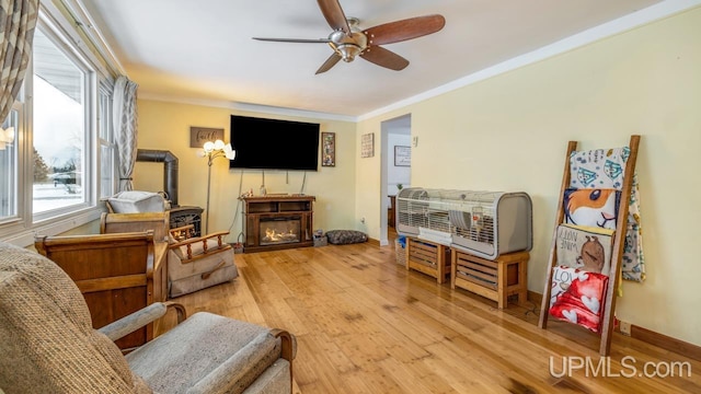 living room featuring ceiling fan, light hardwood / wood-style floors, and crown molding