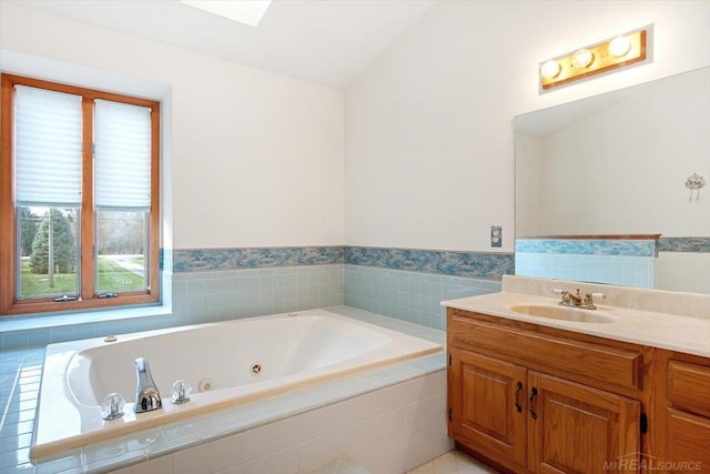 bathroom featuring tiled tub, vanity, and vaulted ceiling