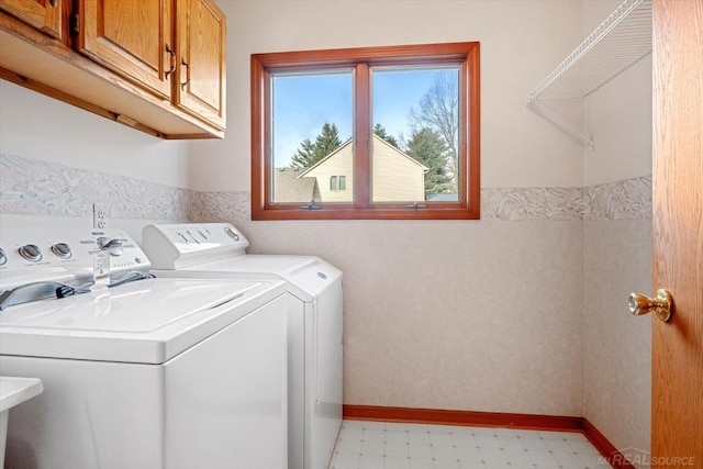 clothes washing area with cabinets and separate washer and dryer