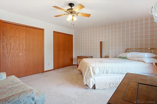 carpeted bedroom with ceiling fan and two closets