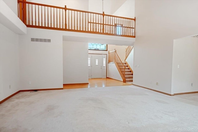 unfurnished living room featuring carpet flooring and a towering ceiling