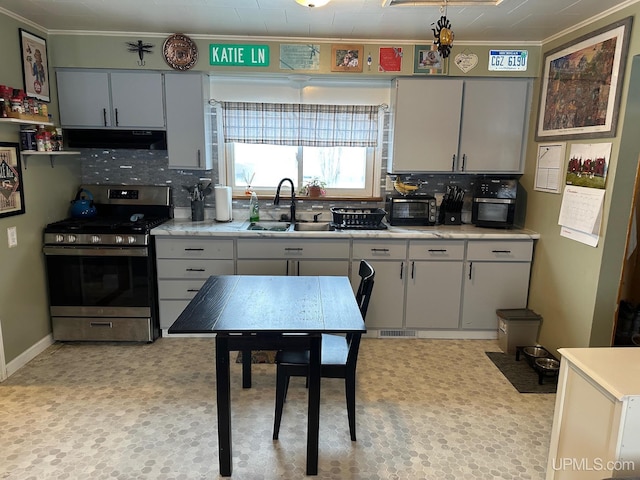 kitchen featuring gray cabinetry, backsplash, sink, stainless steel gas range, and ornamental molding