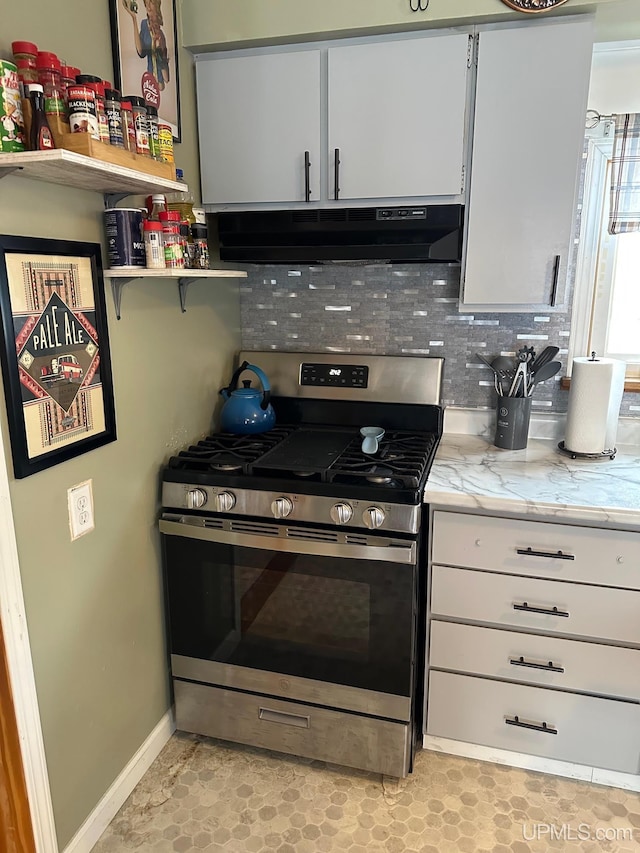 kitchen featuring decorative backsplash, white cabinetry, stainless steel gas range oven, and light stone counters