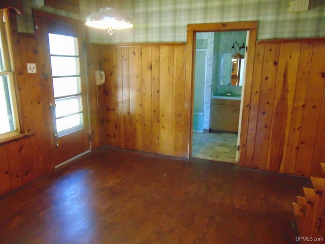 unfurnished room with dark hardwood / wood-style floors, a healthy amount of sunlight, and wooden walls