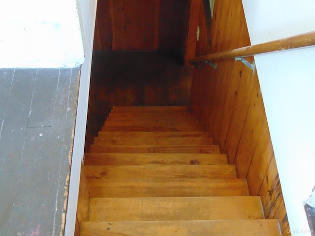 stairway featuring wood walls and hardwood / wood-style flooring