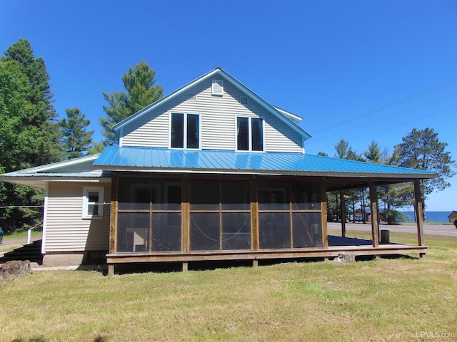 rear view of property with a yard and a sunroom