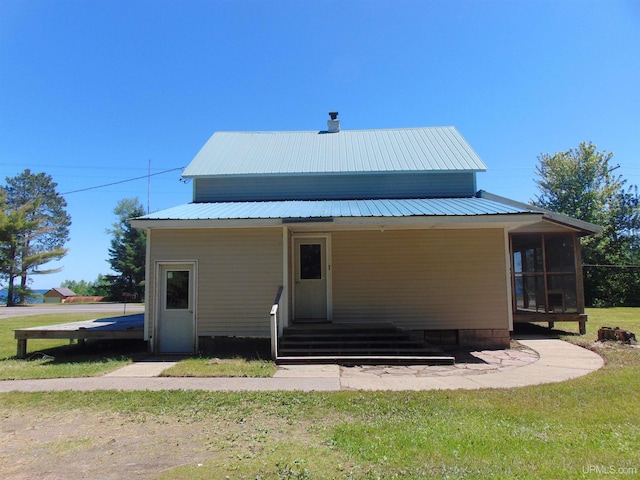 rear view of house featuring a yard and a sunroom