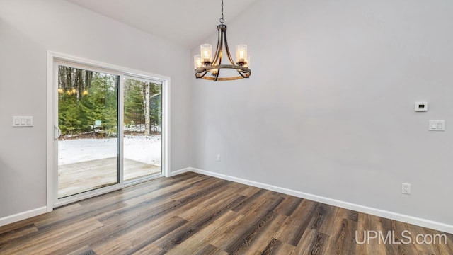 empty room with dark hardwood / wood-style floors and a notable chandelier