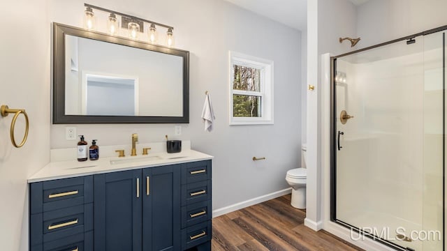 bathroom with wood-type flooring, toilet, walk in shower, and vanity