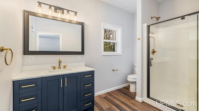 bathroom with toilet, vanity, a shower with door, and hardwood / wood-style flooring