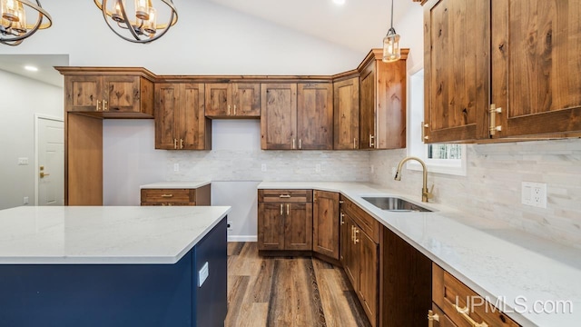 kitchen featuring an inviting chandelier, dark wood-type flooring, light stone countertops, pendant lighting, and sink