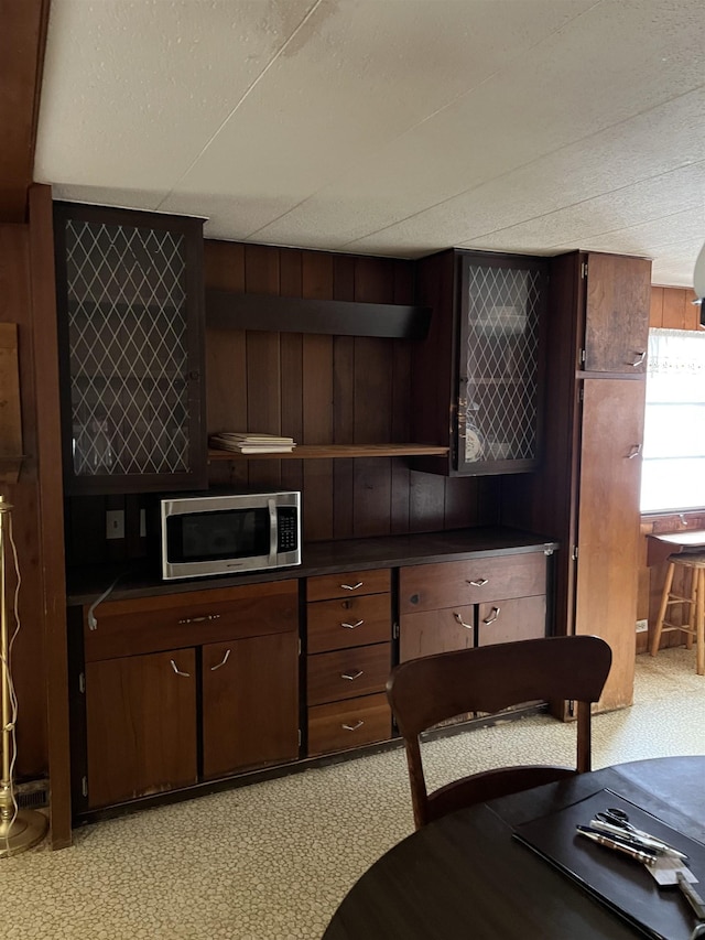 kitchen with light carpet, a textured ceiling, dark brown cabinetry, and wooden walls