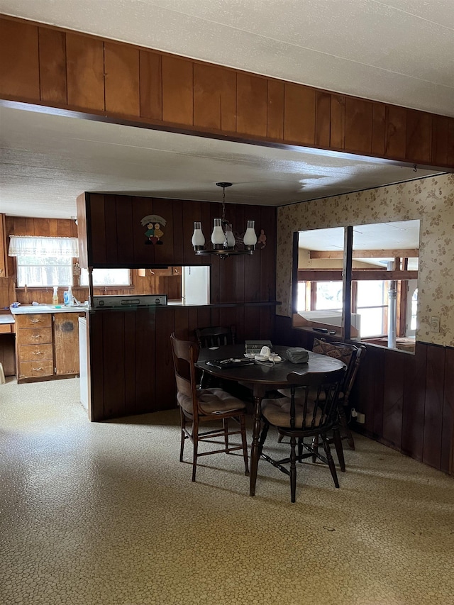 dining area featuring light colored carpet, a wealth of natural light, a notable chandelier, and wood walls