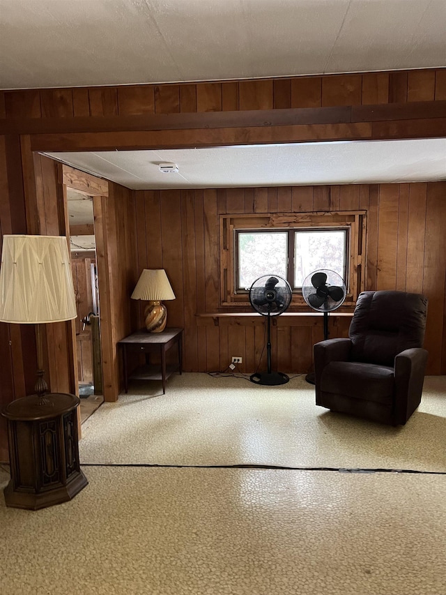 sitting room featuring carpet, a textured ceiling, and wooden walls